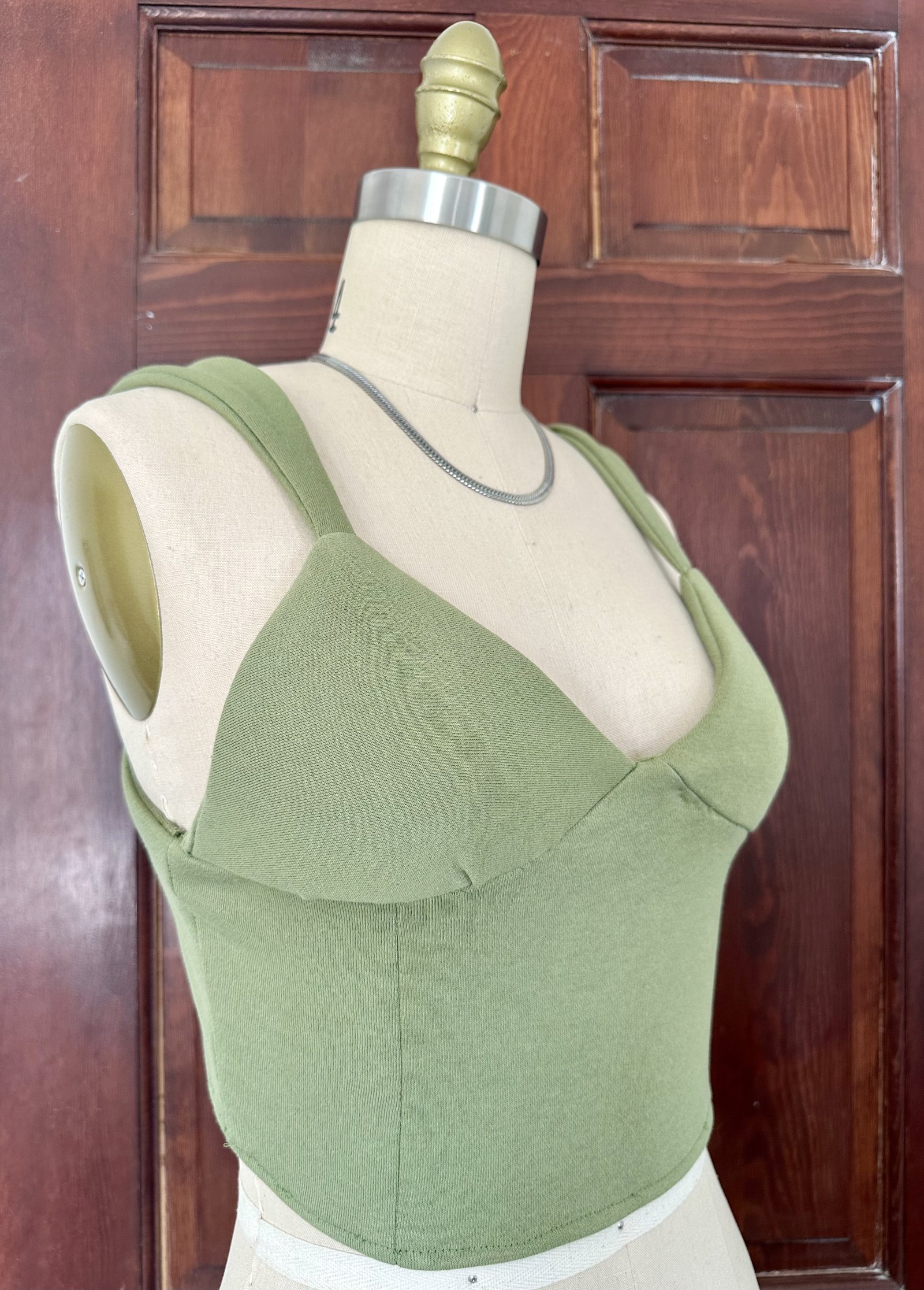 Sage green corset crop top in jersey on dress form