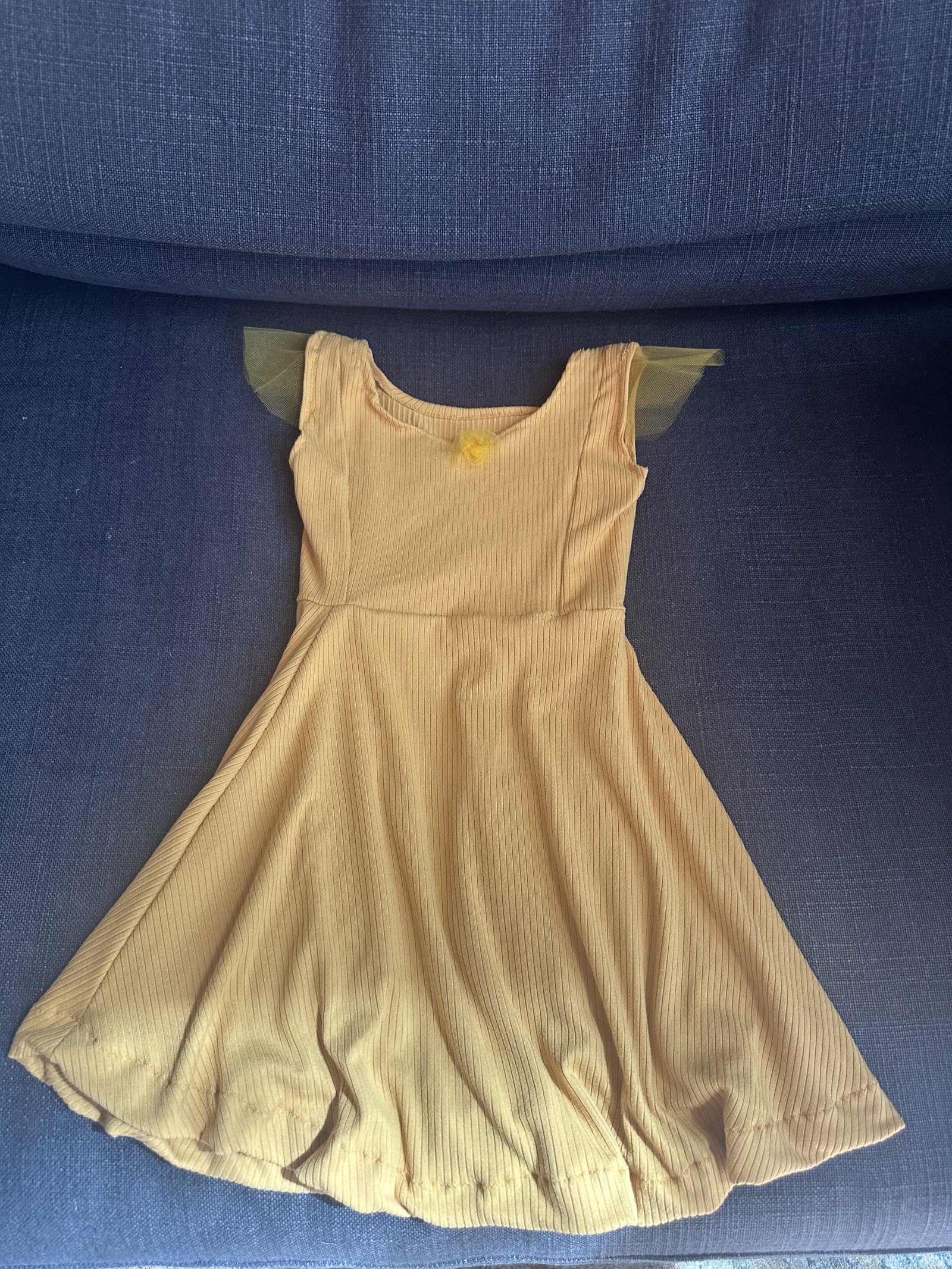 Mustard ribbed jersey dress with flutter cap sleeves on a navy couch