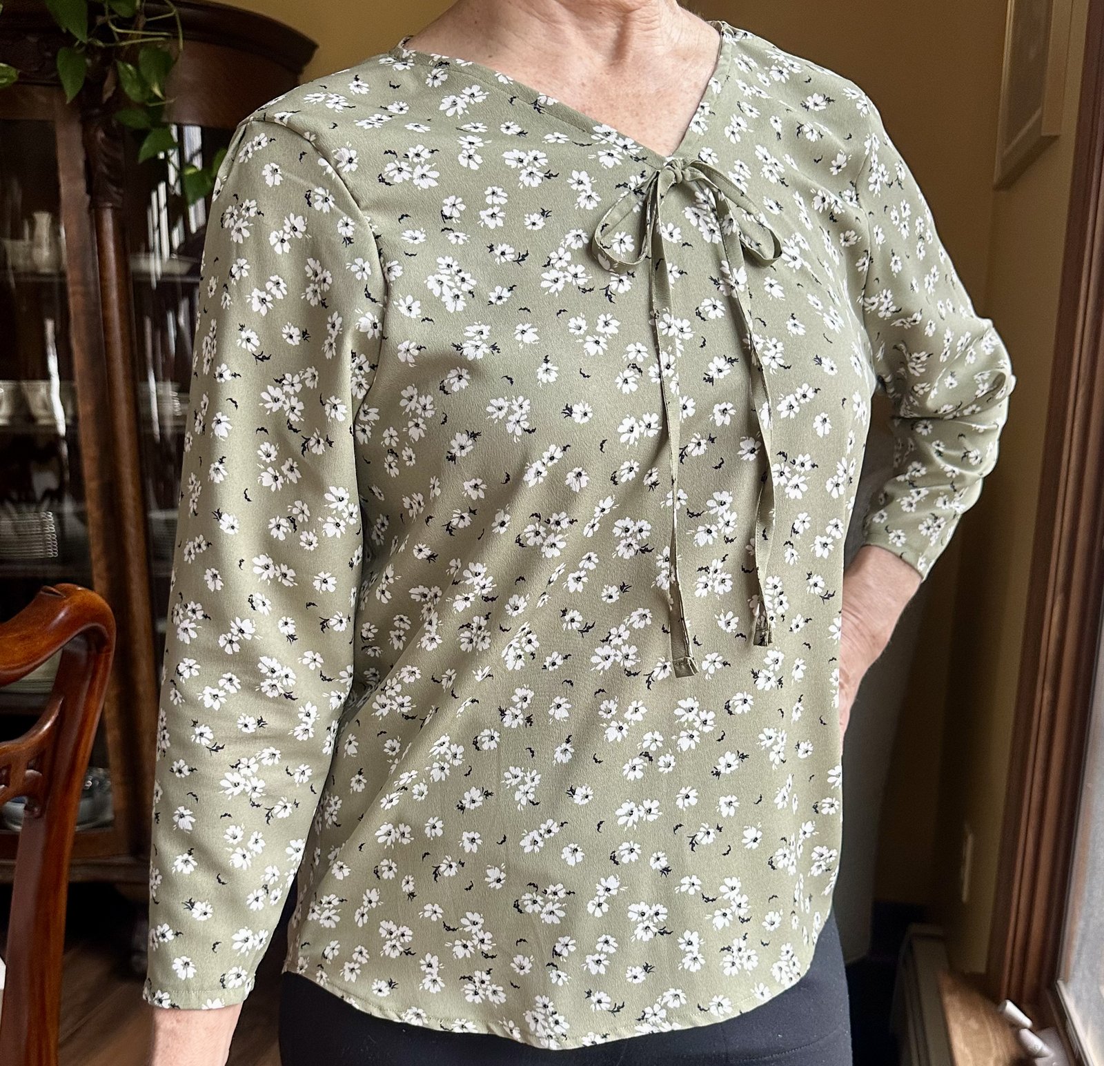 Client wearing a sage floral chiffon blouse with bow detail