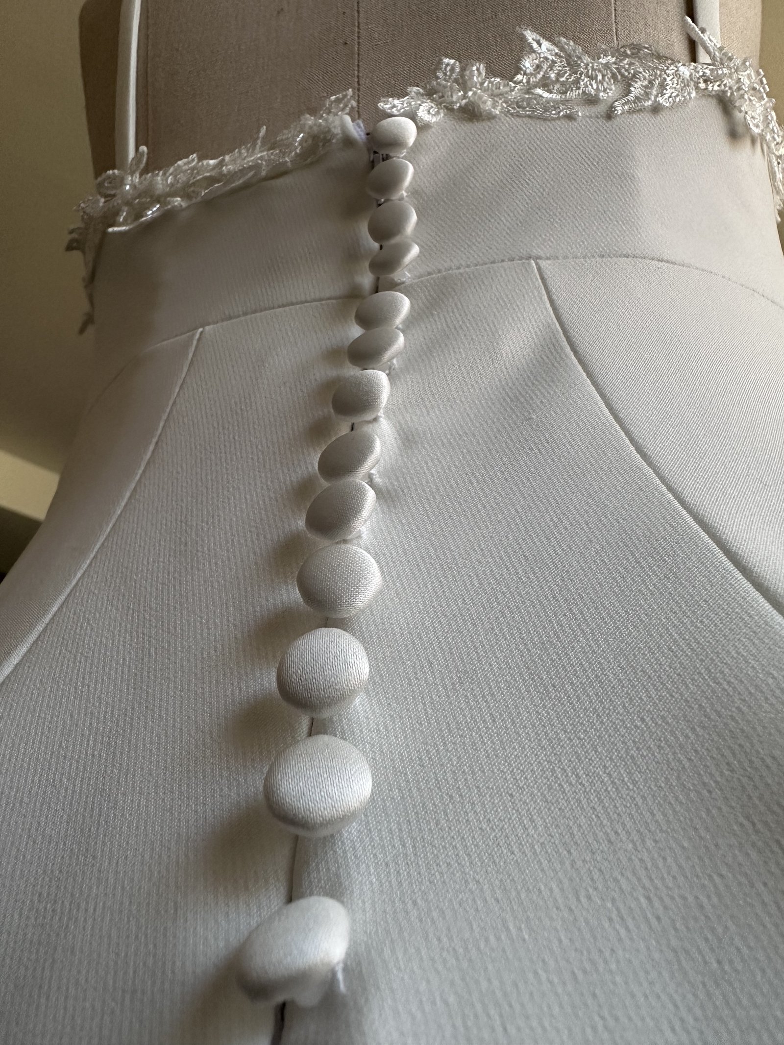 Hand-set satin button placket along the spine of a couture wedding gown