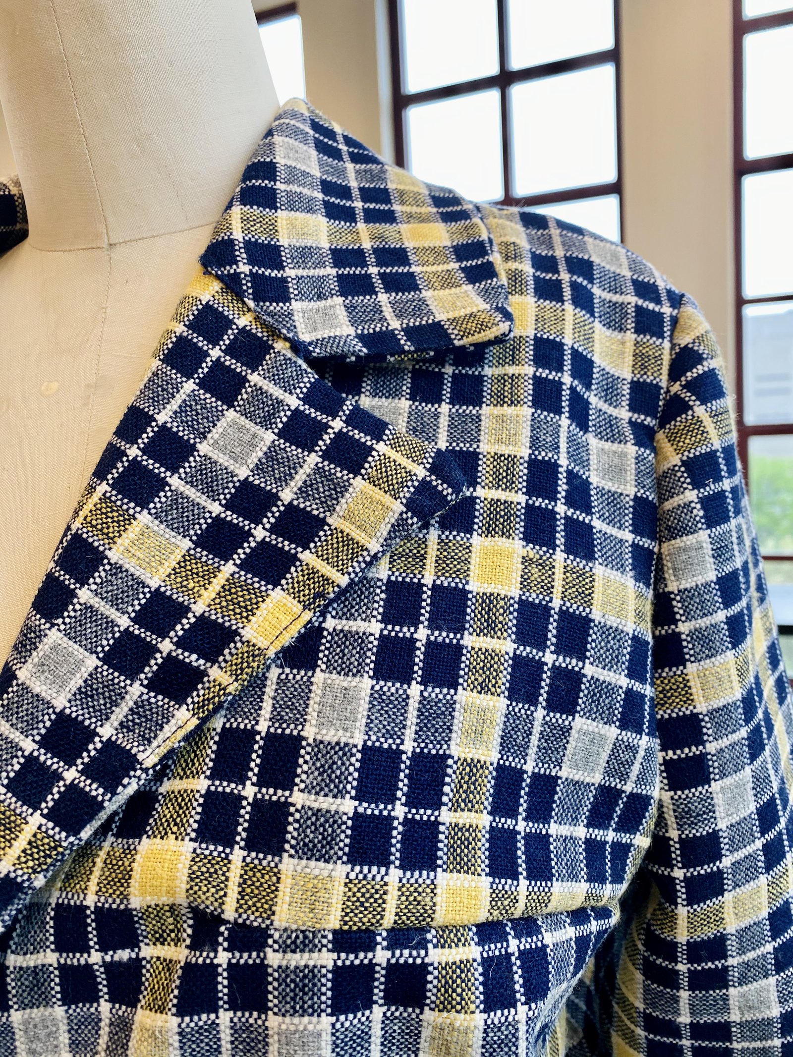 Detail of a hand-set notch lapel on a navy and yellow plaid trench coat