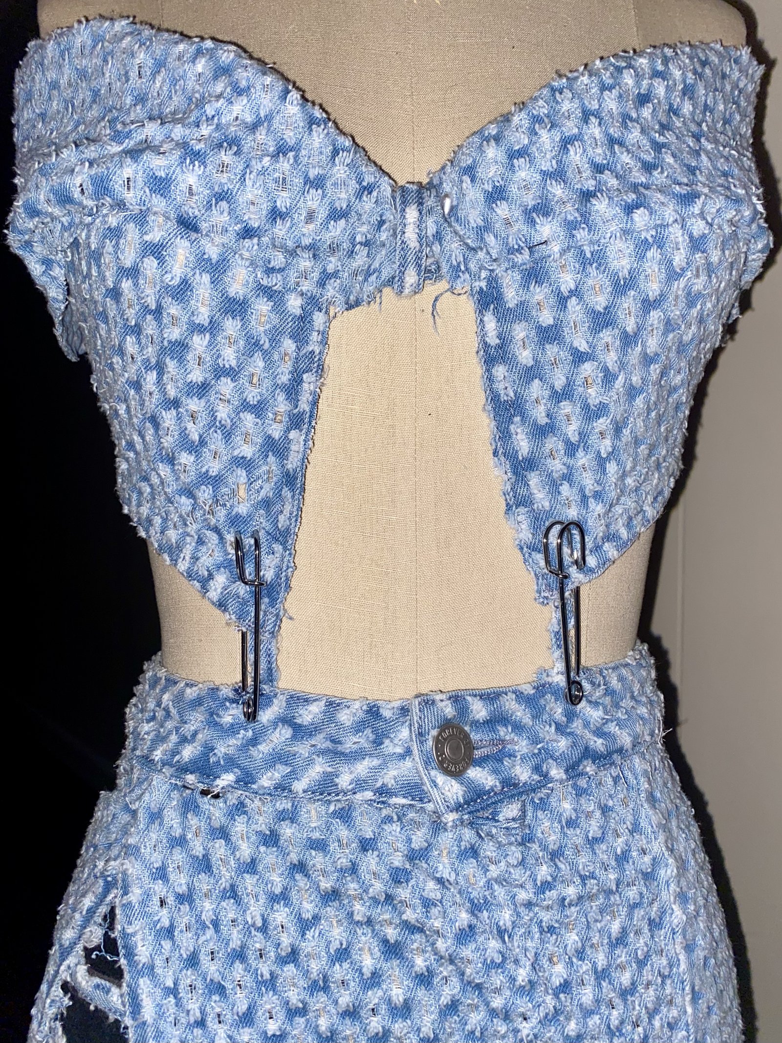 Close-up of a denim corset bustier with safety-pin detailing