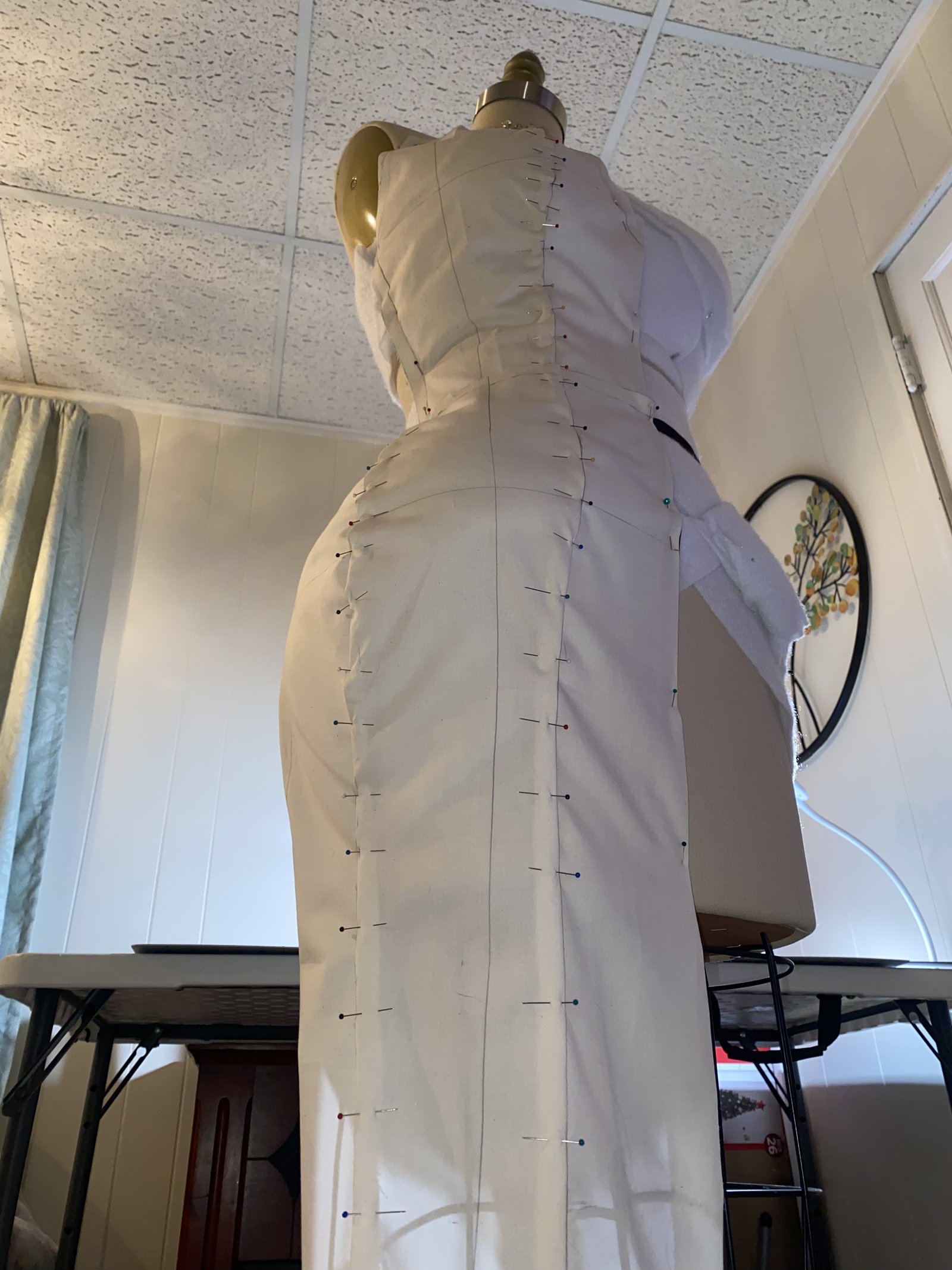 Floor-length mermaid silhouette muslin toile pinned on a dress form